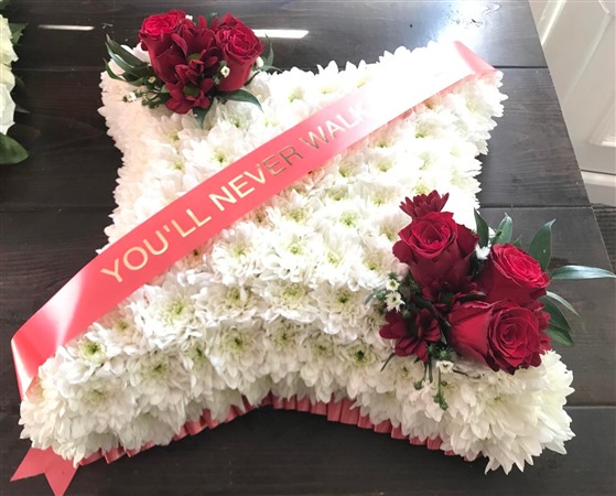 Cushion. Massed with red rose sprays. You'll Never Walk Alone Banner. Liverpool FC Funeral Tribute.